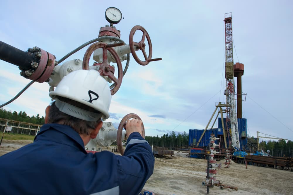 A drilling rig worker standing in front of the oil rig