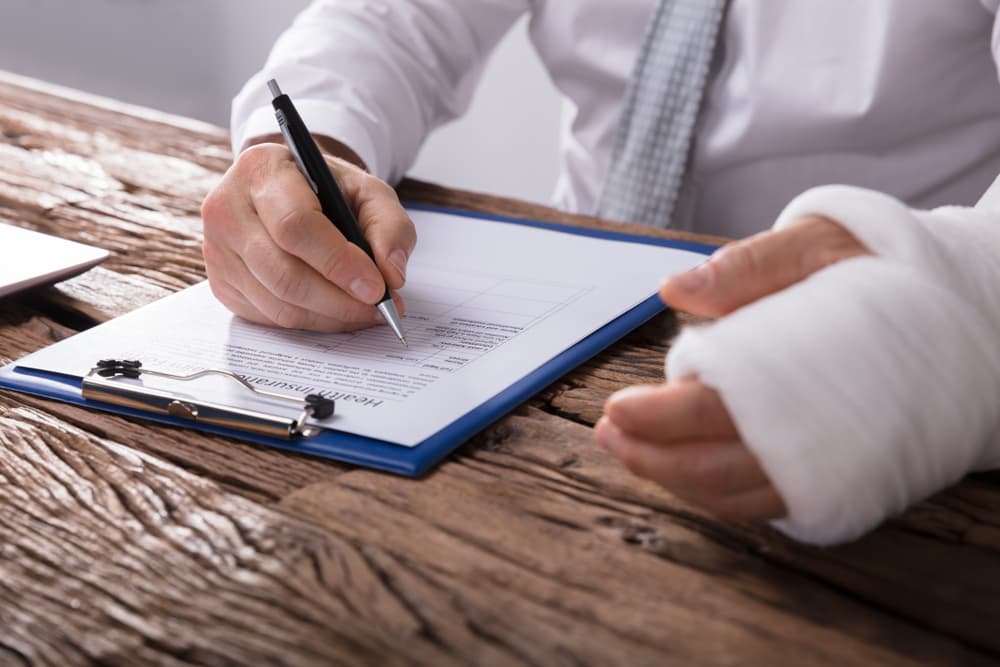 A man with broken Arm Filling Health Insurance Claim Form after a accident in oil field