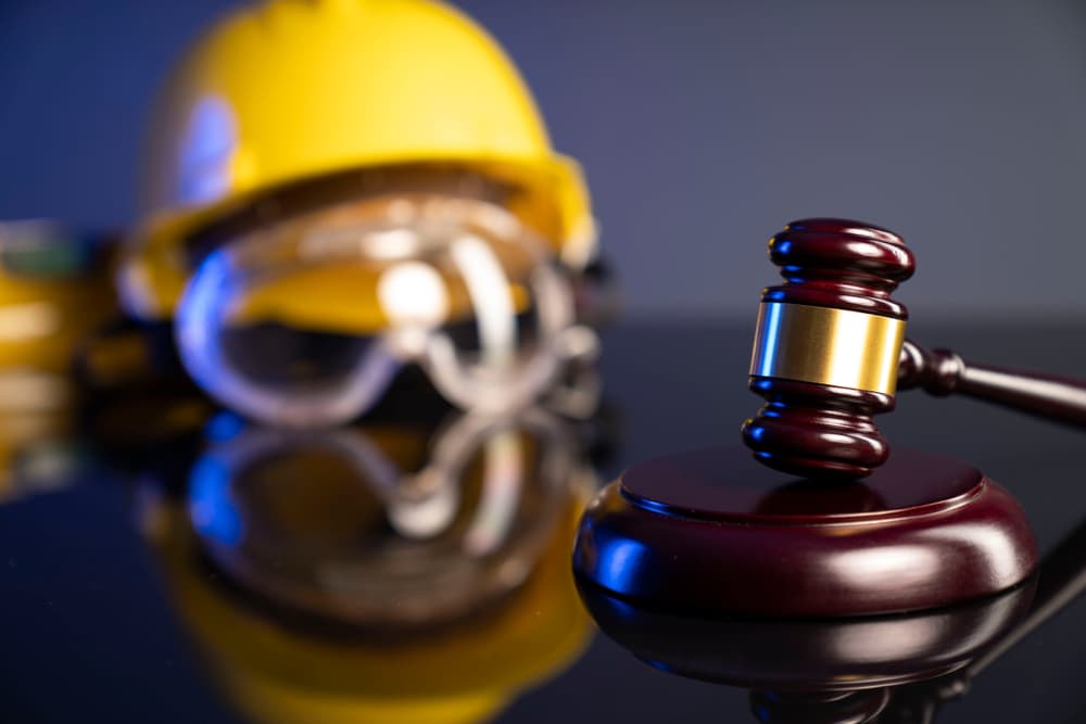 Helmet on desk with gavel symbolizing workers compensation law