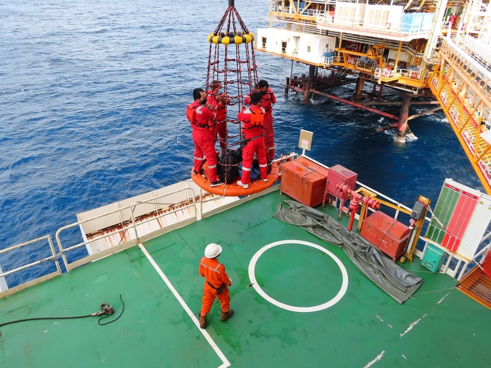 Workers are lifted by the crane to the offshore platform, Transfer crews by personal basket from the platform to crews boat.