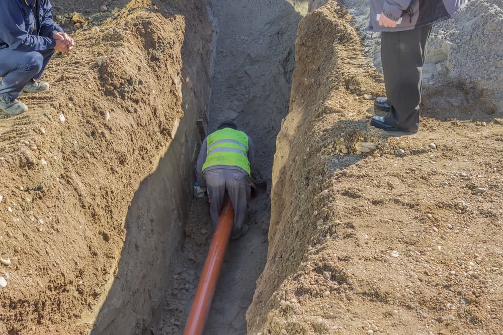 Worker working in trench. No ladder, no hardhat, not working in the trench box. Dangers of trench collapse.