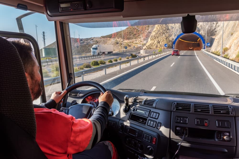 Truck driver, seen from inside the cab, driving on the highway